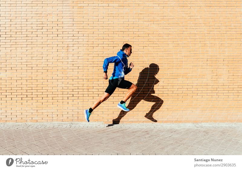Ein gutaussehender Mann, der in der Stadt herumläuft. rennen Joggen Läufer Straße Großstadt Athlet Geschwindigkeit Fitness Lifestyle Jugendliche Aktion Schatten