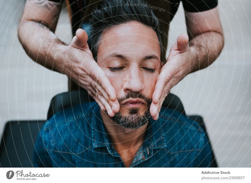 Barbier macht Gesichtsmassage bei einem gutaussehenden Mann. Massage Stil geschlossene Augen professionell sitzen Stuhl Behandlung Gesundheit Therapie