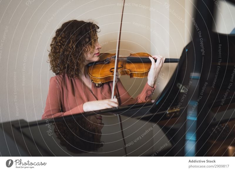 Frau, die neben einem Klavier sitzt und eine Geige spielt. herumfuchteln Spielen Musik Geiger Orchester Instrument Klassik Musiker Hand Musical Mensch Schnur