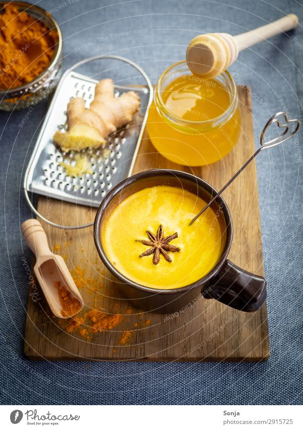 Goldene Milch mit Honig und Ingwer Lebensmittel Milcherzeugnisse Kräuter & Gewürze Curcuma Sternanis Ernährung Getränk Heißgetränk Tasse Schneidebrett Reibe