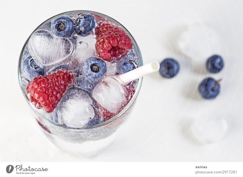 Eisgekühltes Erfrischungsgetränk im Glas mit Beeren, Herz und Eiswürfel Getränk Frucht Himbeeren Blaubeeren Trinkwasser Trinkhalm Gesunde Ernährung Gesundheit