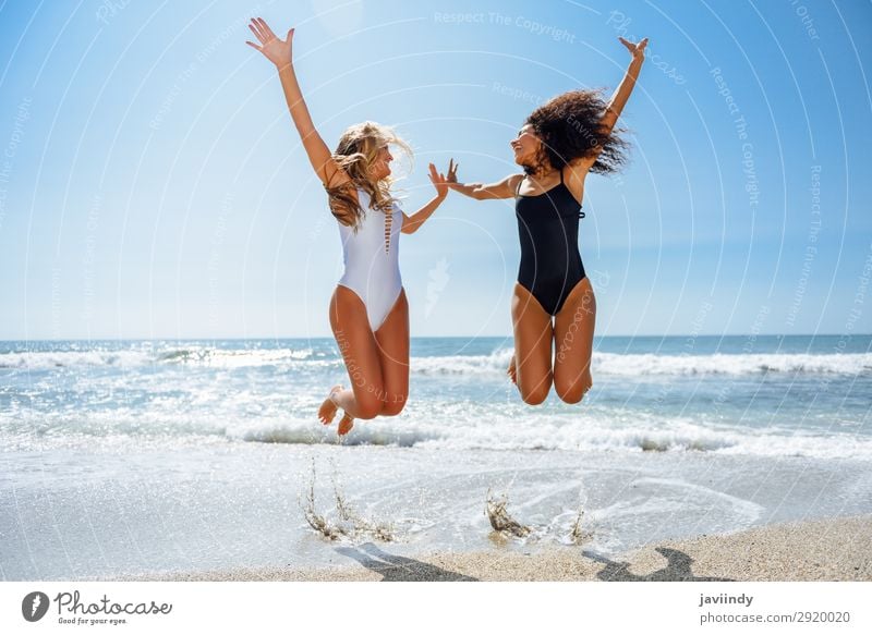 Zwei lustige Mädchen im Badeanzug springen an einem tropischen Strand im Sommer. Lifestyle Freude Glück schön Körper Haare & Frisuren Freizeit & Hobby