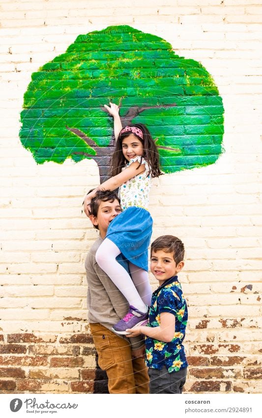 Drei Kinder spielen mit einem Baum, der an einer Wand gemalt ist. Lifestyle Freude Glück Freizeit & Hobby Spielen Kinderspiel Freiheit Sommer Sommerurlaub