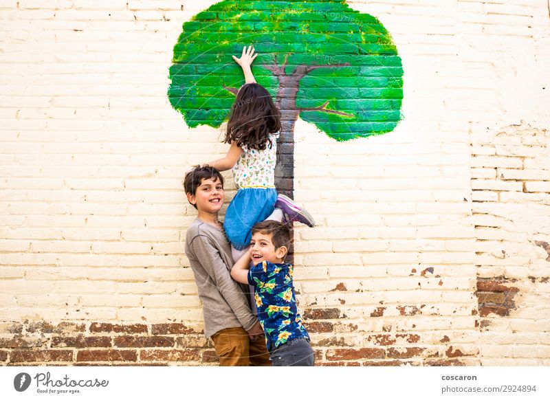 Drei Kinder spielen mit einem Baum, der an einer Wand gemalt ist. Lifestyle Freude Glück schön Freizeit & Hobby Spielen Ferien & Urlaub & Reisen Freiheit Sommer
