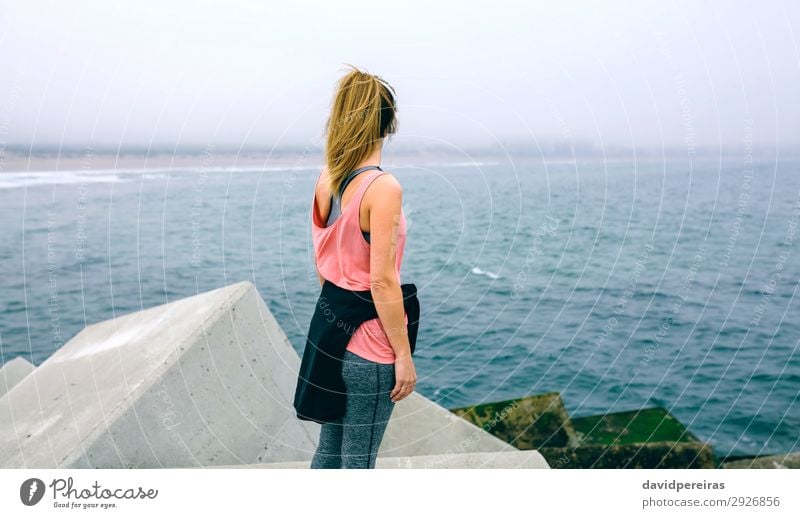 Nicht erkennbare junge Frau, die das Meer beobachtet. Lifestyle Wellness Erholung ruhig Sport Mensch Erwachsene Nebel Beton beobachten Fitness sportlich
