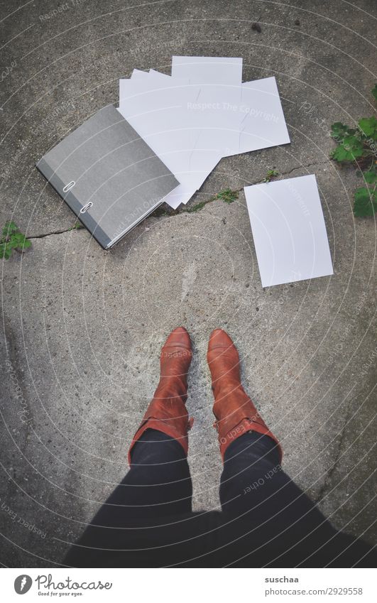 frau steht auf der straße vor einem heruntergefallenem aktenorder mit herausfallenden blättern Beine Frau stehen Stiefel weiblich Aktenordner