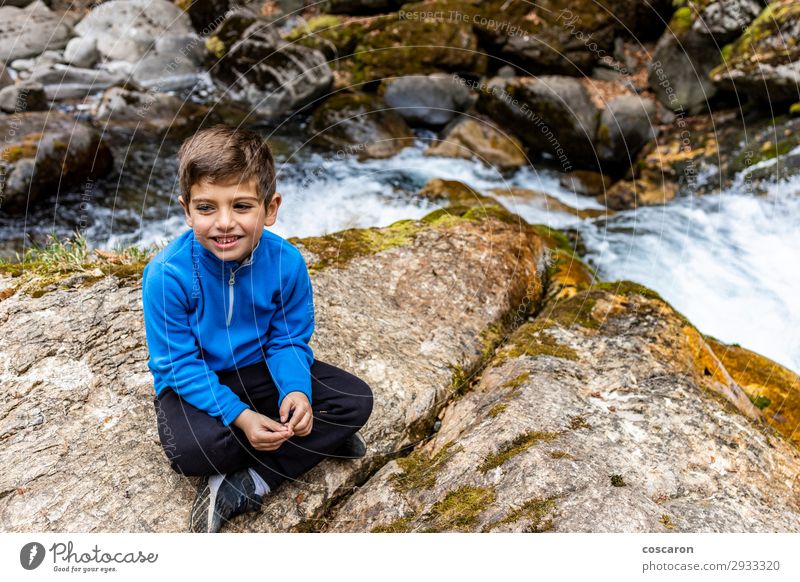 Süßer kleiner Junge sitzt in der Nähe eines wilden Flusses. Lifestyle Stil Freude Glück schön Freizeit & Hobby Ferien & Urlaub & Reisen Expedition Sommer