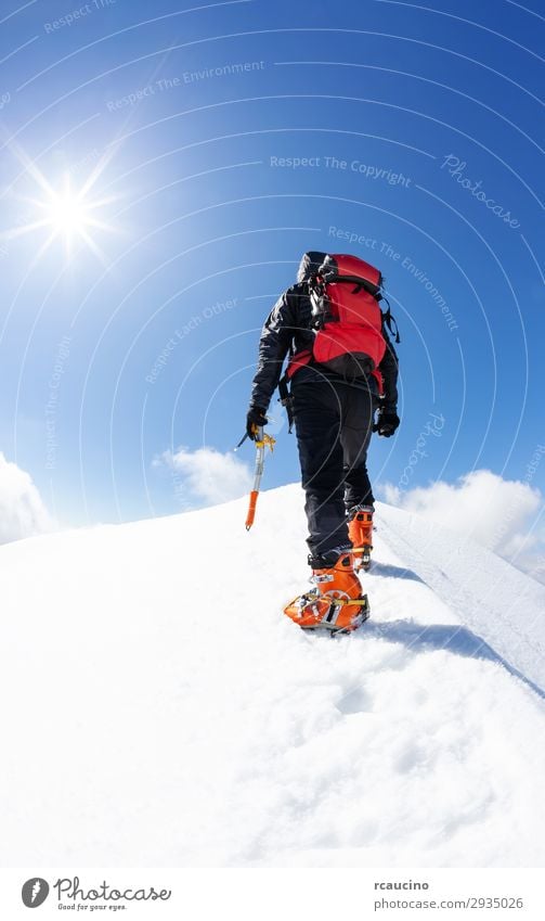 Ein Bergsteiger erreicht den Gipfel eines verschneiten Berges Freude Ferien & Urlaub & Reisen Abenteuer Freiheit Expedition Winter Schnee Berge u. Gebirge Sport