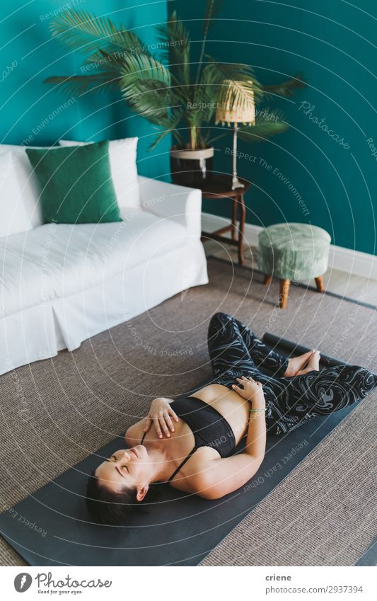 junge Frau entspannt sich beim Yoga im Wohnzimmer Lifestyle Glück schön Körper Wellness Meditation Haus Sport Mensch Erwachsene Pflanze Fitness Lächeln grau