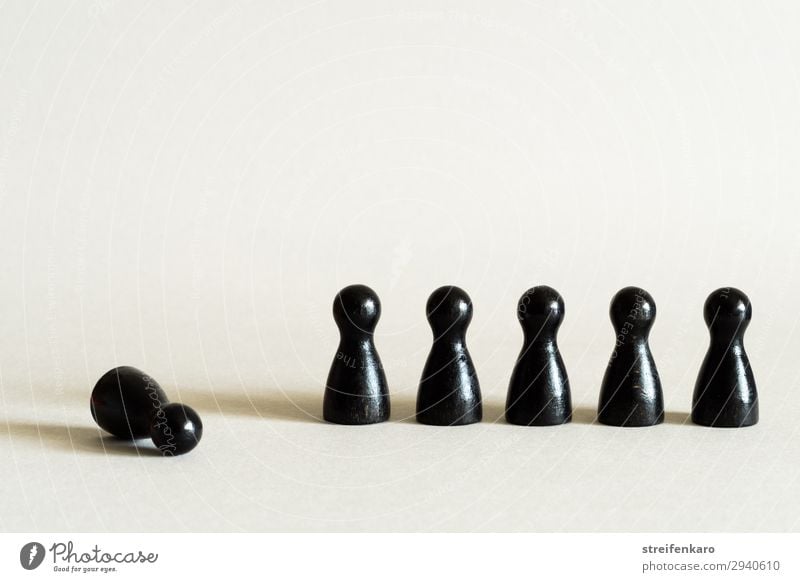Einzelne schwarze Spielfigur liegt abseits neben einer Reihe weiterer schwarzer Spielfiguren Spielen Wirtschaft Team Arbeitslosigkeit Menschengruppe Spielzeug