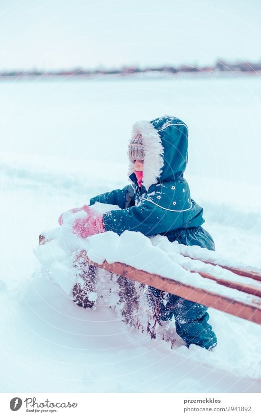 Kleines Mädchen genießt den Winter und entfernt Schnee von einer Bank. Lifestyle Freude Glück Spielen Kind Mensch Frau Erwachsene Kindheit 1 Natur Landschaft
