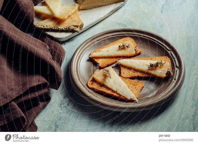 Halbgereifter Käse Rosmarin auf geröstetem Brot geschnitten Lebensmittel Bioprodukte Vegetarische Ernährung Diät Gastronomie alt dunkel frisch lecker natürlich