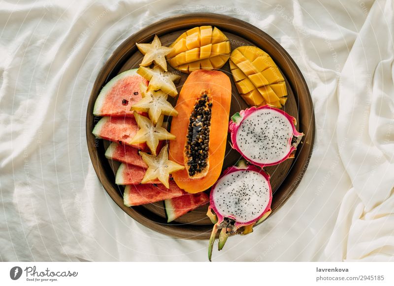Verschiedene exotische tropische Früchte auf einem Metalltablett im Bett Schlafzimmer Frühstück Karambole geschnitten lecker Dessert Diät Drachenfrucht flach