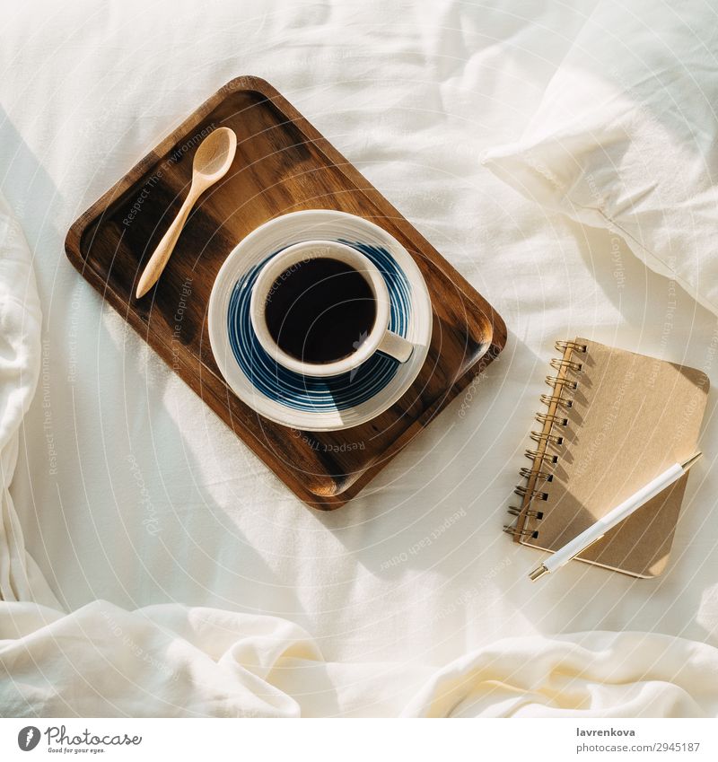 Kaffee auf Holztablett mit Notizbuch und Stift auf dem Bett Hintergrund neutral Schlafzimmer Getränk Frühstück braun Tasse flach Flachlegung heiß legen Morgen