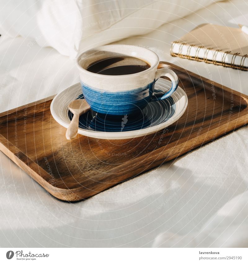 Kaffee auf Holztablett mit Notizbuch und Stift auf dem Bett Hintergrund neutral Schlafzimmer Getränk Frühstück braun Tasse heiß Morgen Becher Papier