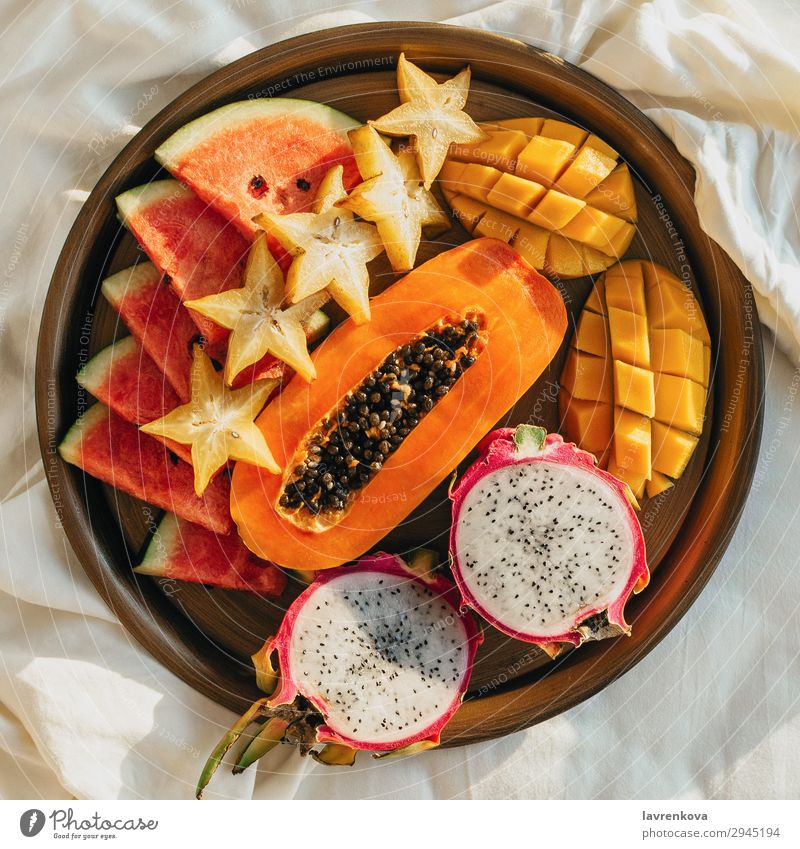 verschiedene exotische tropische Früchte auf einem Metalltablett auf dem Bett Schlafzimmer Frühstück Karambole geschnitten lecker Dessert Diät Drachenfrucht