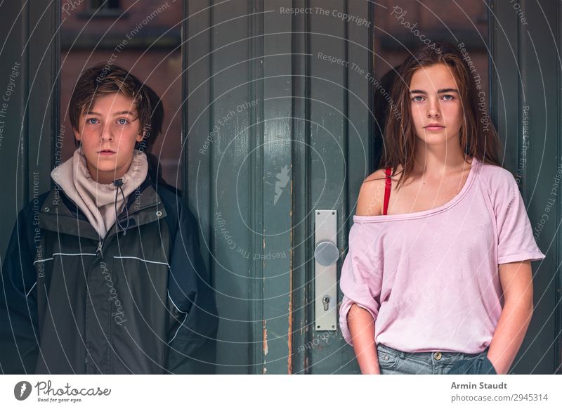 Porträt eines Jungen und eines Mädchens vor einer grünen Tür Teenager Jugendliche zwei Person selbstbewusst Straße im Freien Eingang lässig jung Frau Mann