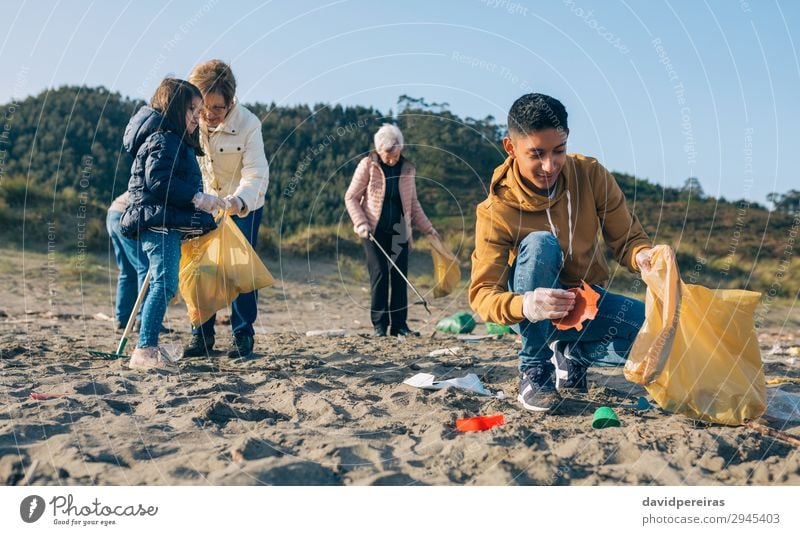 Junger Mann putzt den Strand Arbeit & Erwerbstätigkeit Mensch Erwachsene Familie & Verwandtschaft Hand Menschengruppe Umwelt Sand Kunststoff dreckig Teamwork