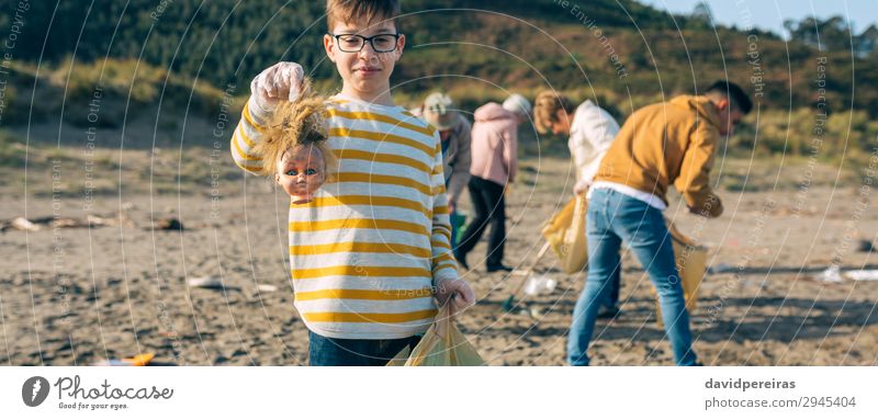 Junge zeigt Puppenkopf beim Putzen des Strandes Kind Arbeit & Erwerbstätigkeit Internet Mensch Frau Erwachsene Mann Familie & Verwandtschaft Menschengruppe