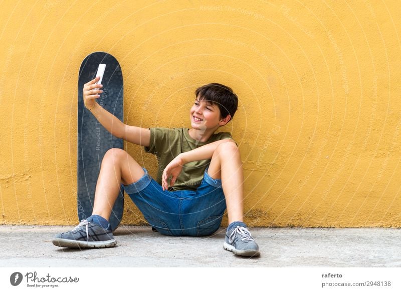 Junge, der auf dem Boden sitzt und sich an eine Wand lehnt und einen Selfie nimmt. Glück Kind Telefon PDA Technik & Technologie Mensch Jugendliche 1 13-18 Jahre