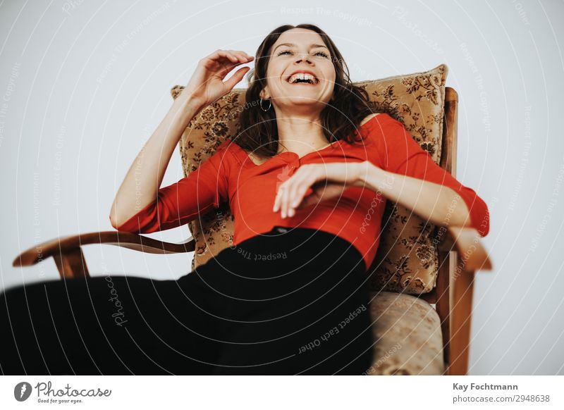 Frau sitzt im Sessel und lacht Lifestyle Zufriedenheit Häusliches Leben Wohnung feminin Junge Frau Jugendliche Erwachsene 18-30 Jahre T-Shirt Hose brünett
