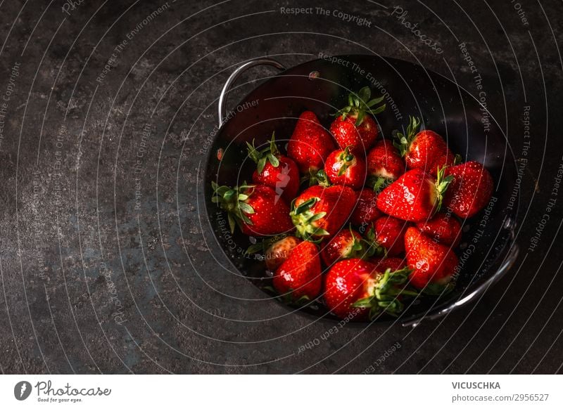 Leckere Erdbeeren in schwarzer Siebschale auf dunklem, rustikalem Küchentisch. Raum kopieren. Saisonale Bio-Lebensmittel. Gesundes Essen und Kochen