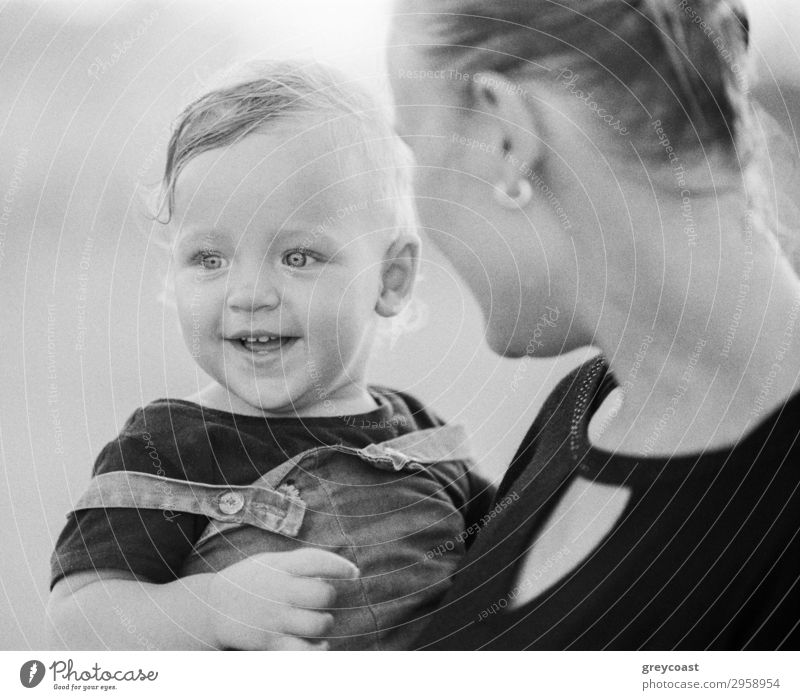 Schwarz-Weiß-Aufnahme der jungen Mutter trägt und Blick auf freudige ein Jahr Baby Mädchen mit Liebe. Glückliche Mutterschaft Stil Freude Kind Mensch Frau