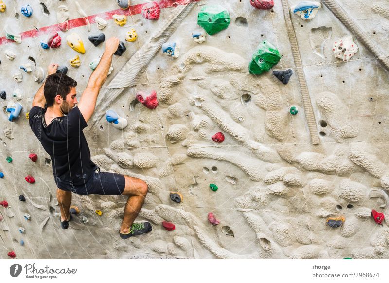 Mann, der an einer künstlichen Wand in der Halle Klettern übt. Aktiver Lebensstil und Boulderkonzept. aktiv schwarz Felsbrocken Bouldern Kreide Herausforderung