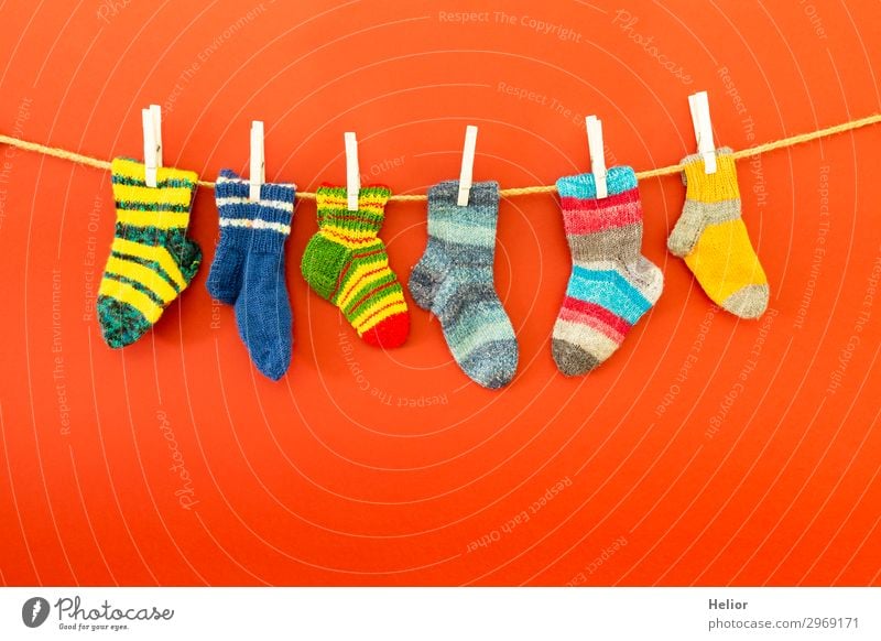 Bunte Socken an einer Wäscheleine auf rotem Hintergrund Stil Design Winter Mode frisch retro Wärme weich blau mehrfarbig grün weiß fleißig Reinlichkeit