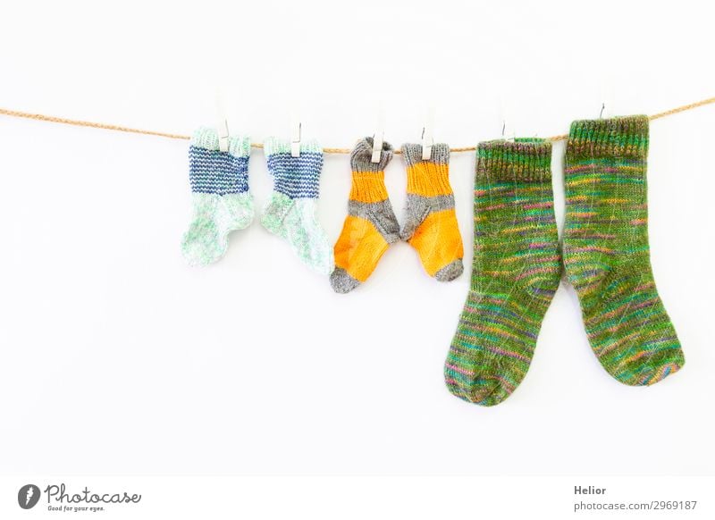 Bunte Socken an einer Wäscheleine auf weissem Hintergrund Stil Design Handarbeit stricken Winter Mode frisch retro Wärme weich gelb grün weiß Ordnungsliebe