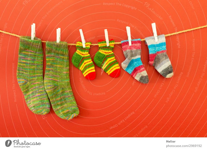 Bunte Socken an einer Wäscheleine auf rotem Hintergrund Stil Design Handarbeit stricken Winter Mode frisch retro trocken Wärme weich blau mehrfarbig grün