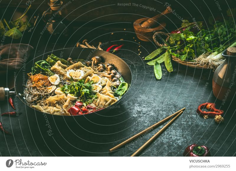 Asiatischer Essenshintergrund mit Wok-Pfanne mit vegetarischem koreanischem Kochtopf und Essstäbchen auf dunklem, rustikalem Küchentischhintergrund, Draufsicht. Platz zum Kopieren.