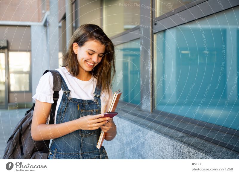 Glückliche Schülerin benutzt Smartphone auf dem Schulkorridor Lifestyle schön Schule Studium Telefon PDA Technik & Technologie Frau Erwachsene Jugendliche