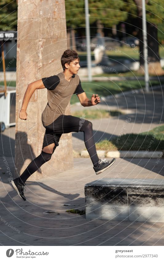 Ein Teenager macht Parkour in einem Stadtpark Sport Leichtathletik Joggen Mensch maskulin Junger Mann Jugendliche 1 13-18 Jahre T-Shirt Turnschuh schwarzhaarig
