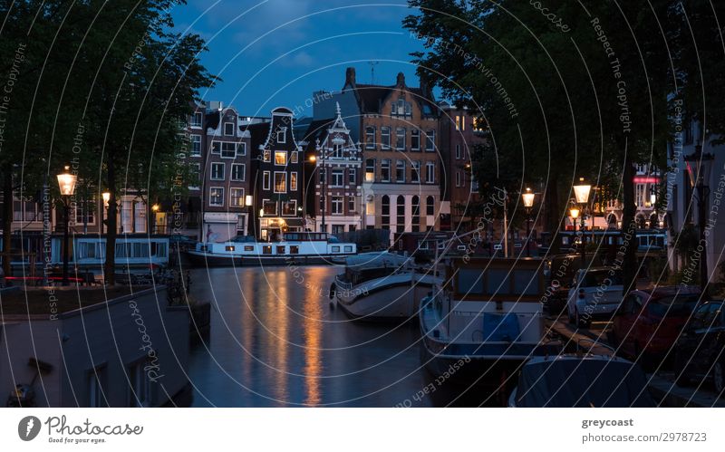 Amsterdamer Nachtszene mit traditionellen Häusern, an der Gracht vertäuten Booten und beleuchteten Laternen, Niederlande Ferien & Urlaub & Reisen Tourismus