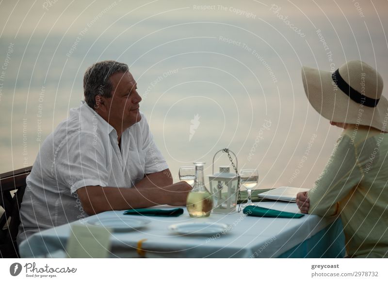 Reifes Paar mit romantischen Abend. Sie genießen die Zeit und Blick auf einander sitzen am Tisch im Restaurant am Meer Abendessen Glück Erholung