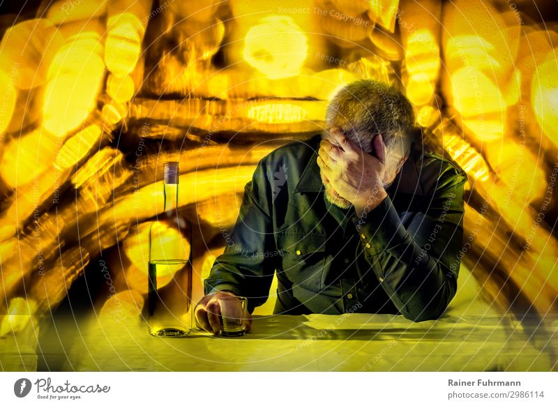 Ein Mann sitzt an einem Tisch und stützt seinen Kopf auf eine Hand. Vor ihm stehen eine Flasche Alkohol und ein Glas. Der Hintergrund leuchtet in grellen Farben.