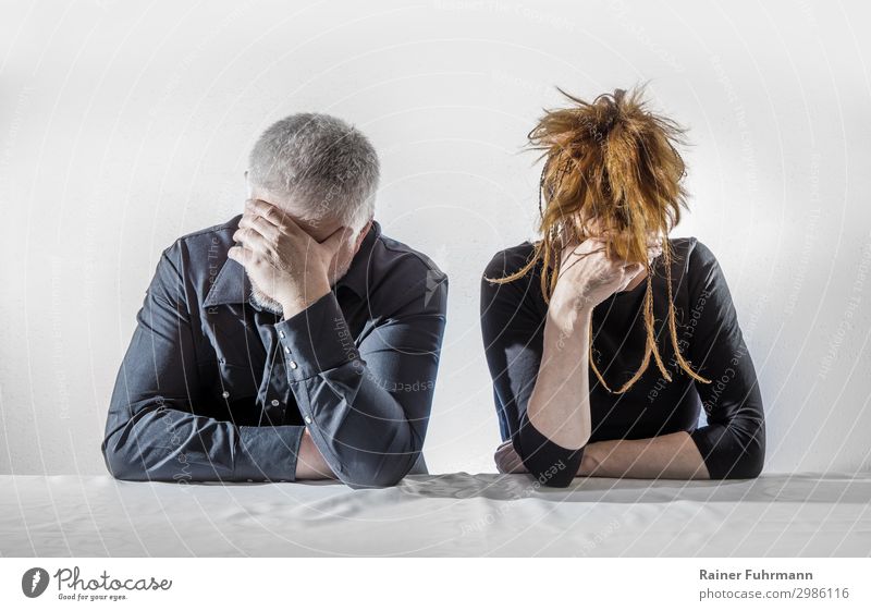 Ein Mann und eine Frau sitzen an einem Tisch, sie wirken deprimiert und schweigen Mensch maskulin feminin Erwachsene 2 Konflikt & Streit Traurigkeit warten