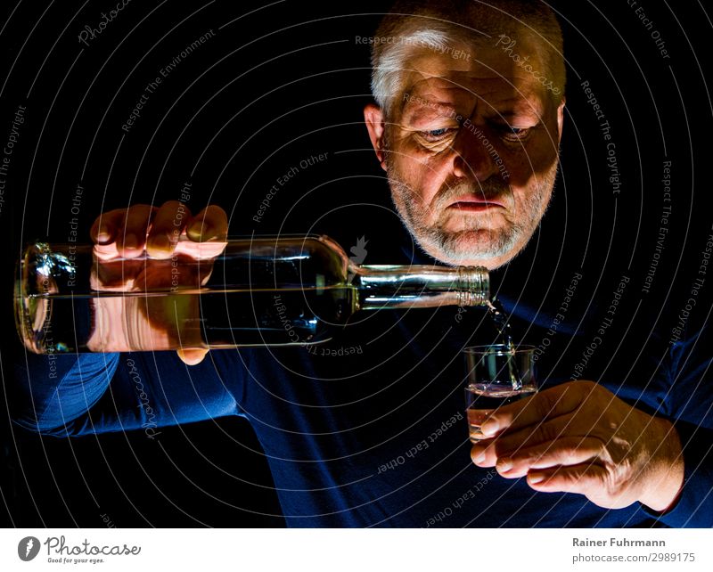Ein Mann gießt Alkohol in ein Glas Mensch maskulin Erwachsene 1 grauhaarig "Flasche Schnapsglas Alkohol" trinken Alkoholsucht Sucht "Alkoholismus Wodka süchtig