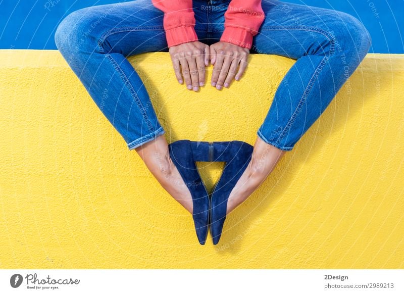 Frau in Jeans sitzt auf einer gelben Wand und macht ein Muster mit Absätzen. Lifestyle Stil schön Leben Erholung Sommer Mensch Erwachsene Fuß Wärme Mode