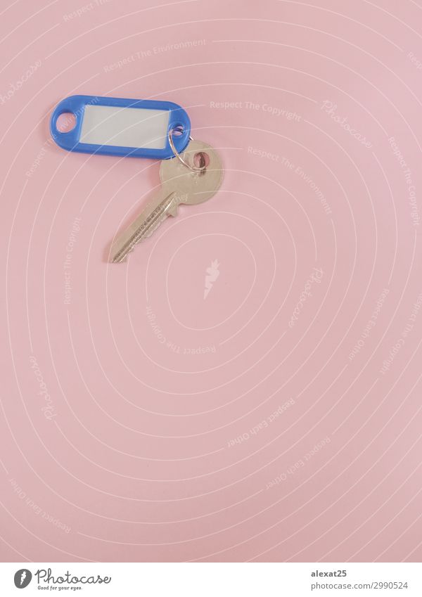 Ein Metallschlüssel mit leerer Beschriftung auf rosa Hintergrund mit Kopiermöglichkeit. Design Haus Business Sicherheit Geborgenheit geheimnisvoll Zugang blanko
