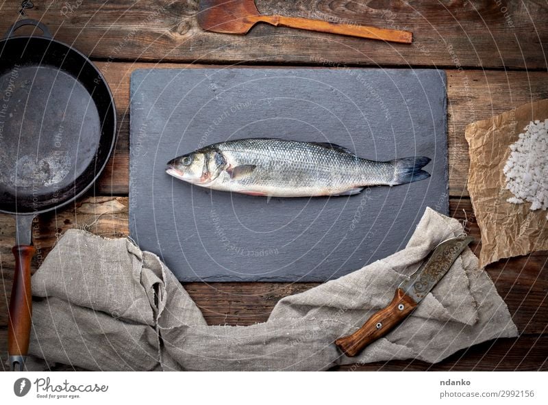 frischer ganzer Seebarschfisch auf einem schwarzen Brett Fleisch Meeresfrüchte Ernährung Abendessen Pfanne Messer Tisch Küche Gastronomie Werkzeug Natur Tier