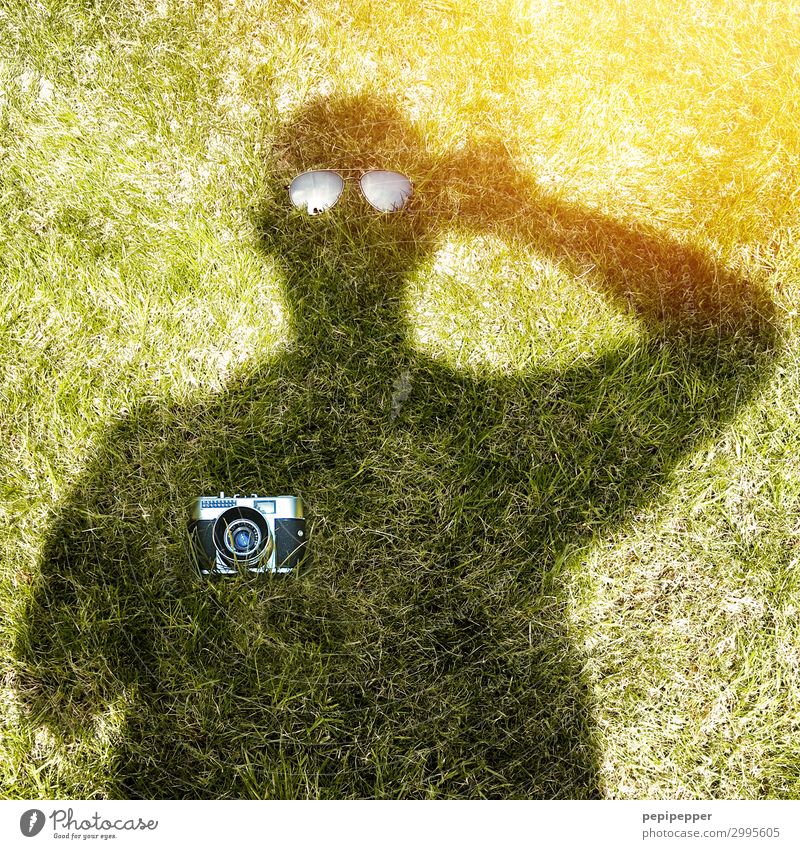 Schattenbild von einem Mann, der einen Fotoapparat und eine Sonnenbrille hält Freizeit & Hobby Garten Mensch maskulin Körper 1 Sonnenlicht Gras Brille