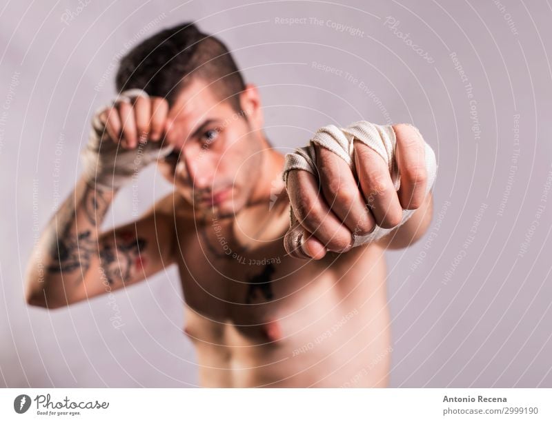 Muai thailändischer Kämpfer, der im Studio posiert und mit Tattoos geschossen wird. Sport Junge Mann Erwachsene Ring Handschuhe Fitness Aggression stark Wut