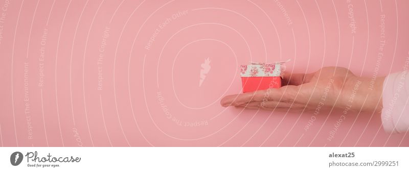 Hand mit einem Geschenk auf rosa Hintergrund mit Kopierfläche Dekoration & Verzierung Feste & Feiern Geburtstag Mensch Frau Erwachsene Papier Paket Schnur weiß