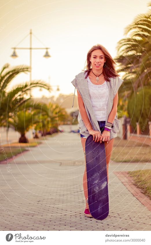 Junges Mädchen mit einem Skateboard im Sommer im Freien. Lifestyle Stil Freude Glück schön Freizeit & Hobby Sport Mensch Frau Erwachsene Jugendliche Wärme Baum