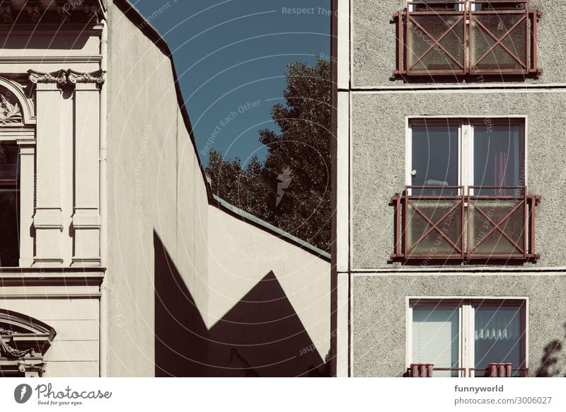 Zwei unterschieldiche Hausfassaden nebeneinander vor einem blauen Himmel Stadt Hochhaus Mauer Wand Fassade eckig trist Fenster Zacken Schatten Häusliches Leben