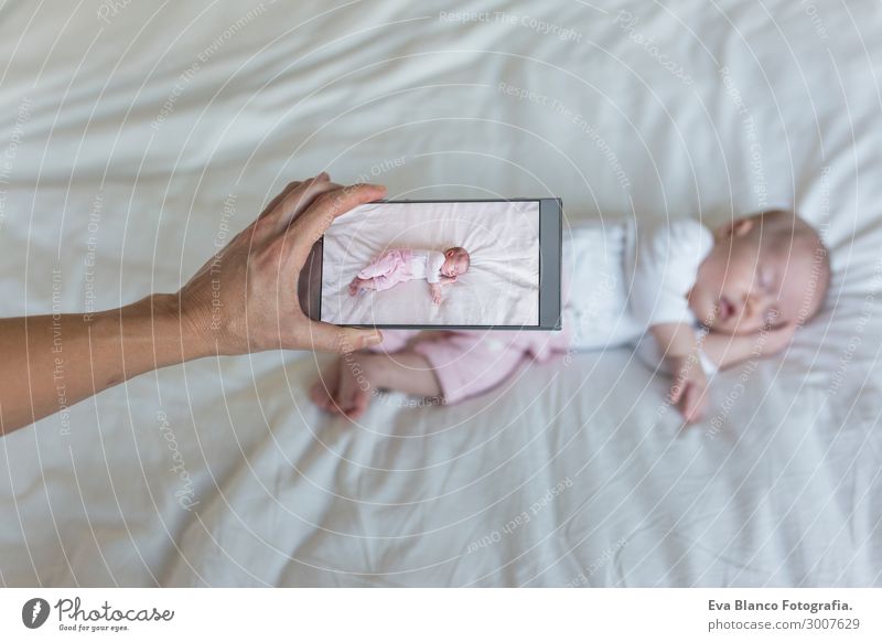 Mutter macht ein Foto von ihrem kleinen Mädchen, das auf dem Bett schläft. schön Haut Gesicht Erholung Kind Telefon Technik & Technologie Internet Baby Hand