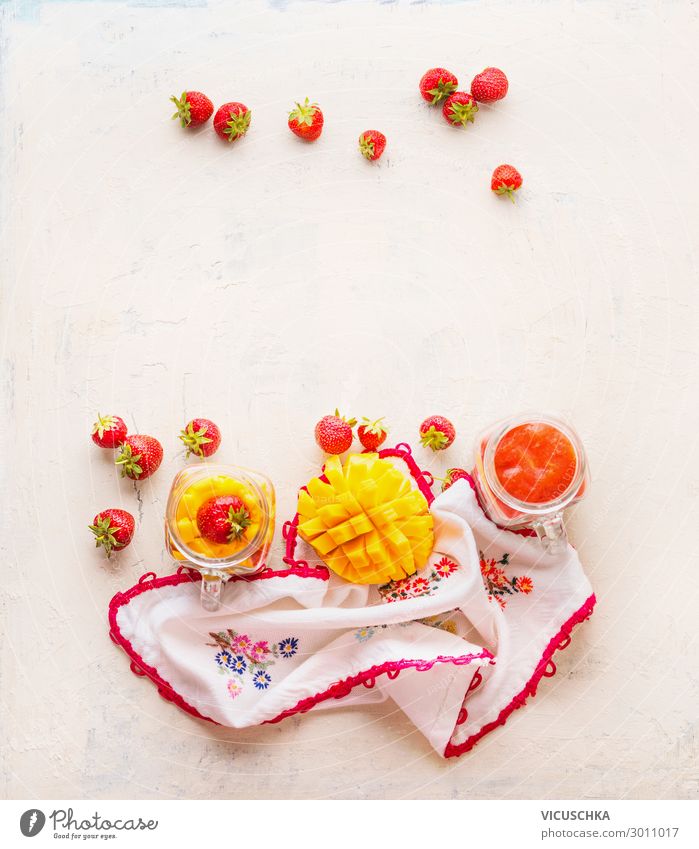 Gesunde Früchte und Beeren im Hintergrund des Frühstücks. Glasgläser mit Erdbeeren und Mangosmoothies auf weißem Tisch . Platz zum Kopieren Gesundheit Gläser