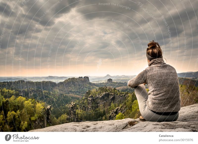 Junge Frau auf einem Felsen im Elbsandsteingebirge blickt in die Landschaft Person junge Frau sitzen beobachten Horizont Wald Felsformation Steine Himmel Wolken